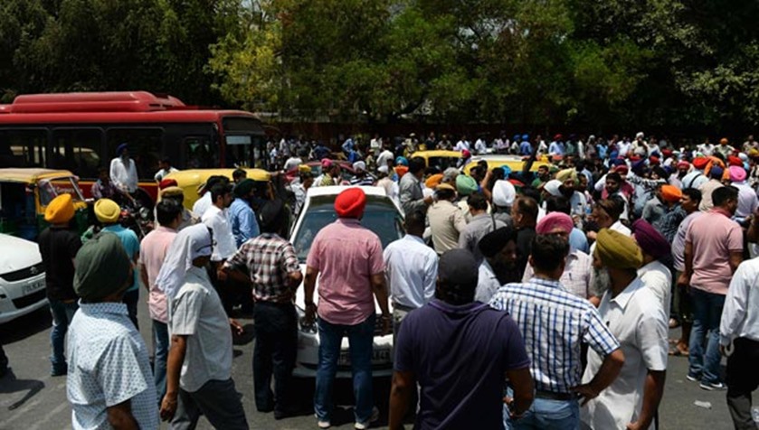 Taxi drivers and owners shout slogans as they block a road in New Delhi