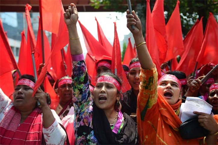 Bangladeshi activists and workers shout slogans and wave flags during a procession in Dhaka
