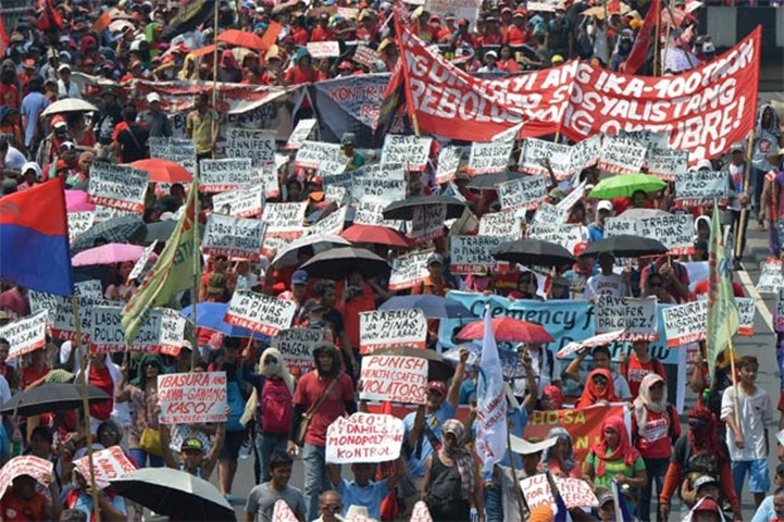 Philippine workers displaying placards and streamers march towards a park in Manila