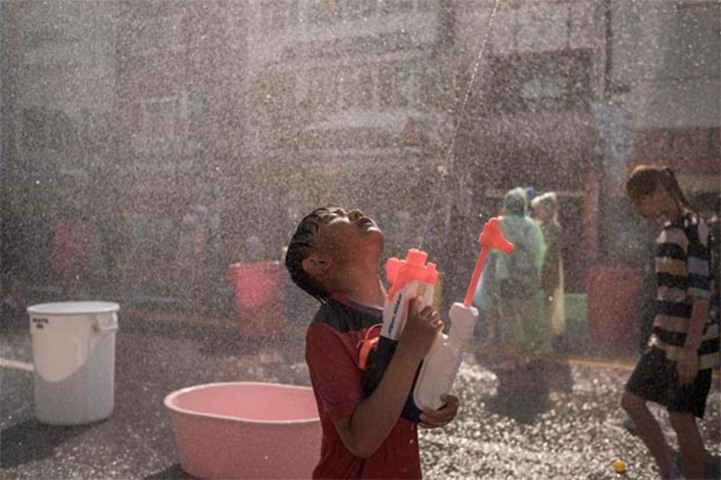 A boy shoots water during a water fight held as part of the festival