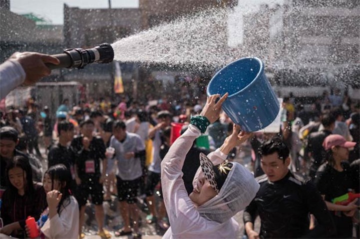 A participant attempts to refill a bucket with water during a water fight