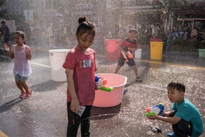 A boy sprays water at a girl during a water fight