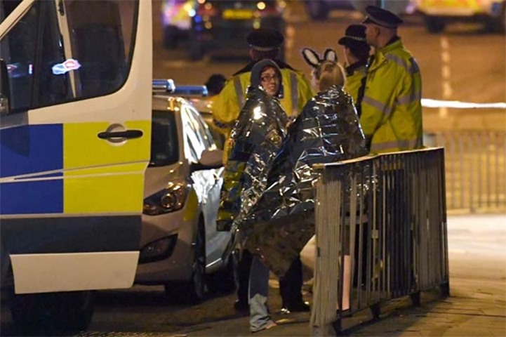 Concert goers wait to be picked up at the scene of the terrorist attack in Manchester