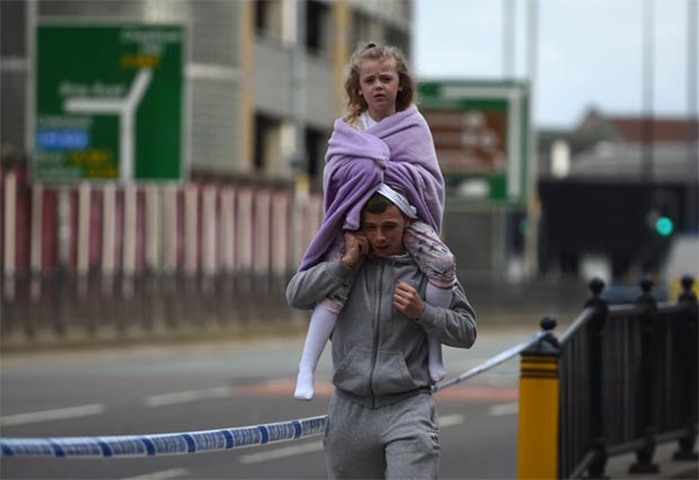 A man carries a young girl on his shoulders near Victoria station in Manchester