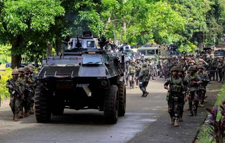 An armoured personnel carrier and government troops march to begin their assault in Marawi City