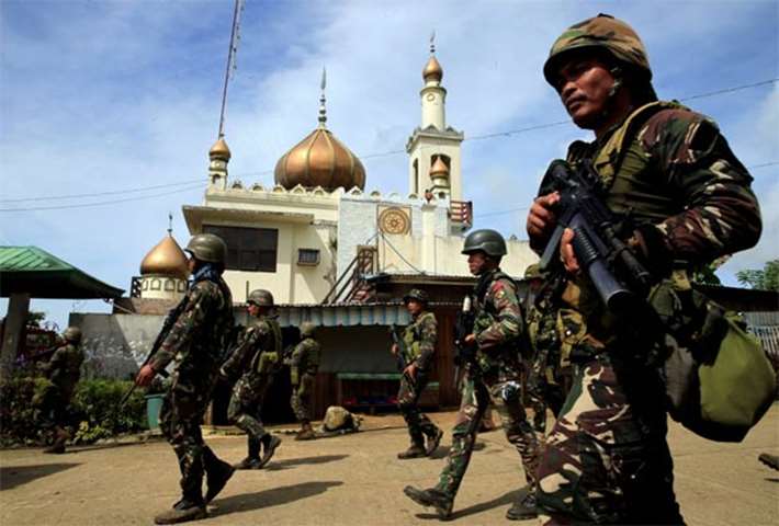 Troops walk past a mosque before their assault with insurgents in Marawi