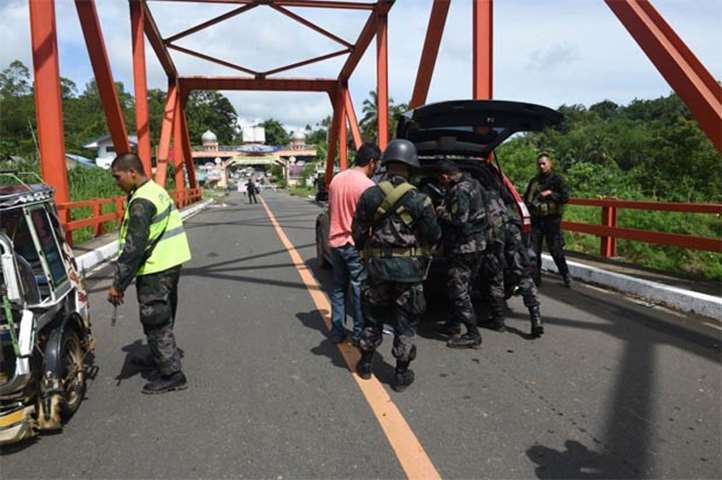 Members of the police special forces check vehicles at a checkpoint near the entrance to Marawi