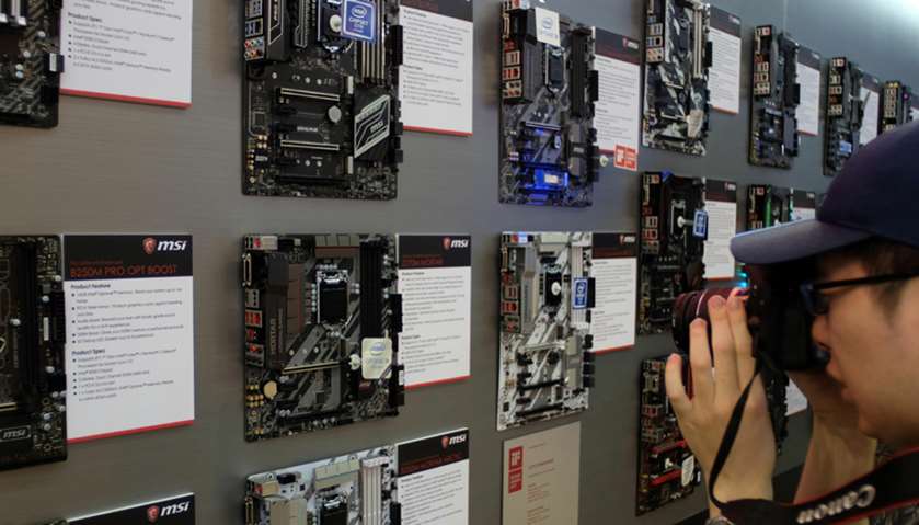 A visitor takes photos of a motherboard wall during the Computex Show