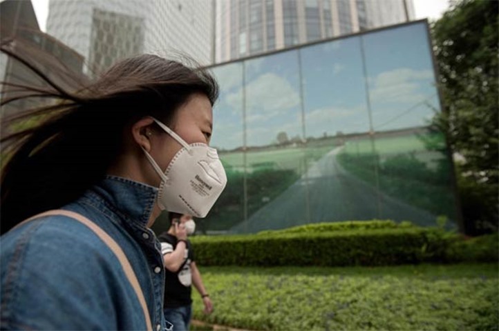 A woman wears a face mask to combat the poor air quality covering Beijing