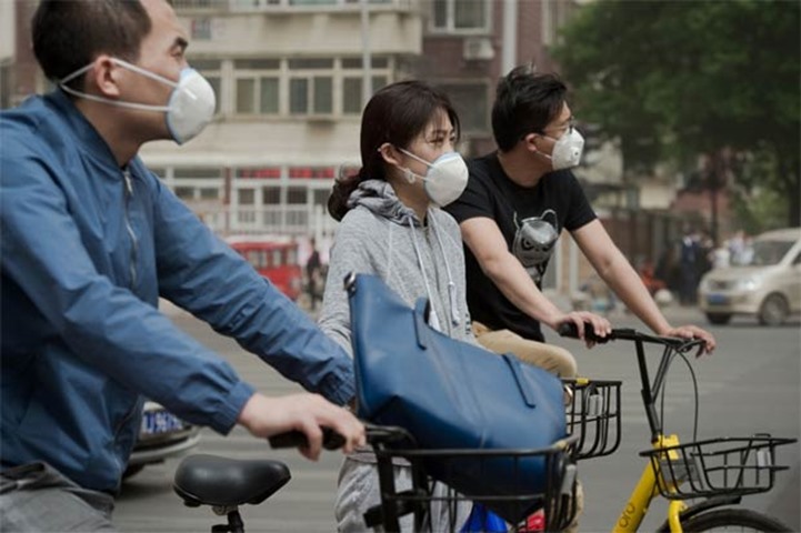 People riding bicycles wear face masks to combat the poor air quality covering Beijing