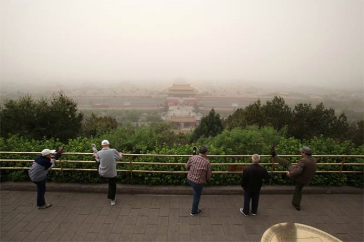 People exercise during a dust storm day in Beijing on Thursday