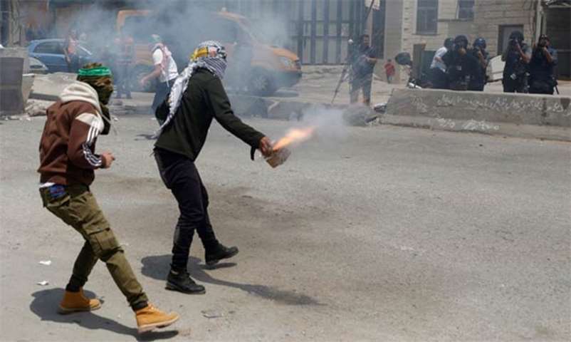 A Palestinian demonstrator releases firecrackers towards Israeli troops near Ramallah