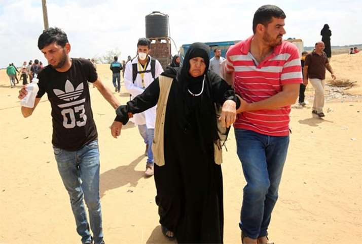 Palestinians help a protester during clashes with Israeli forces along the border with Gaza Strip