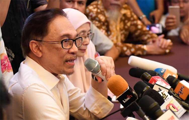 Anwar Ibrahim speaks to the media as his wife Wan Azizah looks on