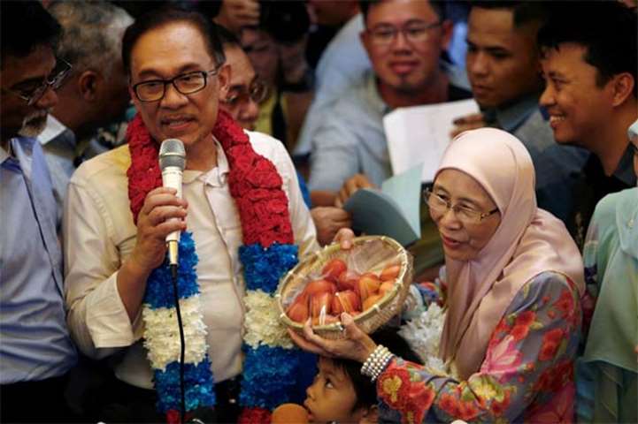 Malaysian politician Anwar Ibrahim speaks during a news conference next to his wife Wan Azizah