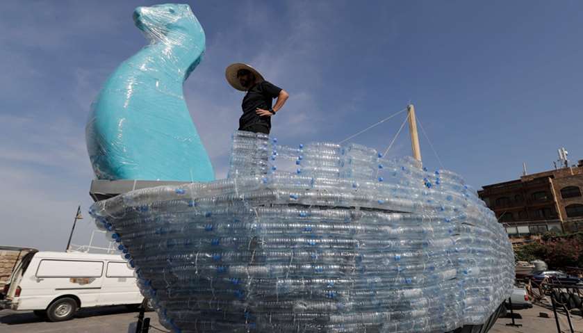 Activists build a boat from plastic water bottles at the ancient port of the Lebanese coastal city o