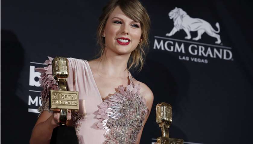 Taylor Swift holds her awards for Top Female Artist and Top Selling Album.