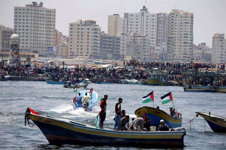 People watch as Palestinians prepare to sail a boat at the sea in Gaza on Tuesday