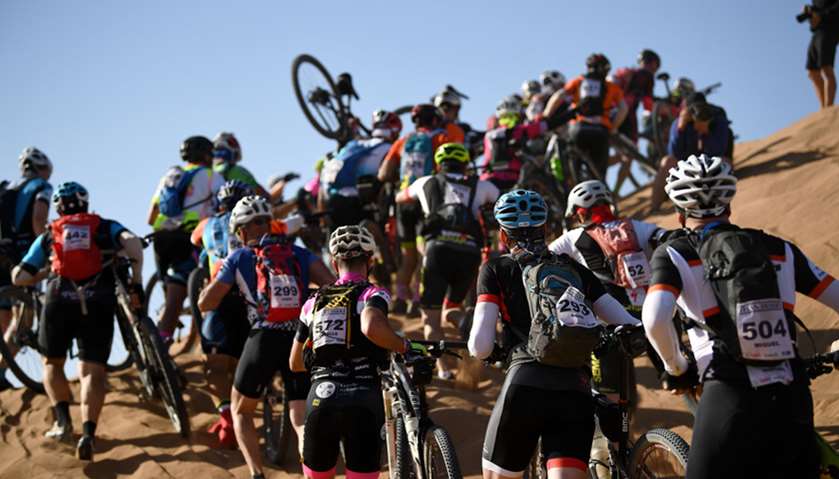 Competitors push their bikes up a sand dune during the biking race between Boumalne Dades and Merzou