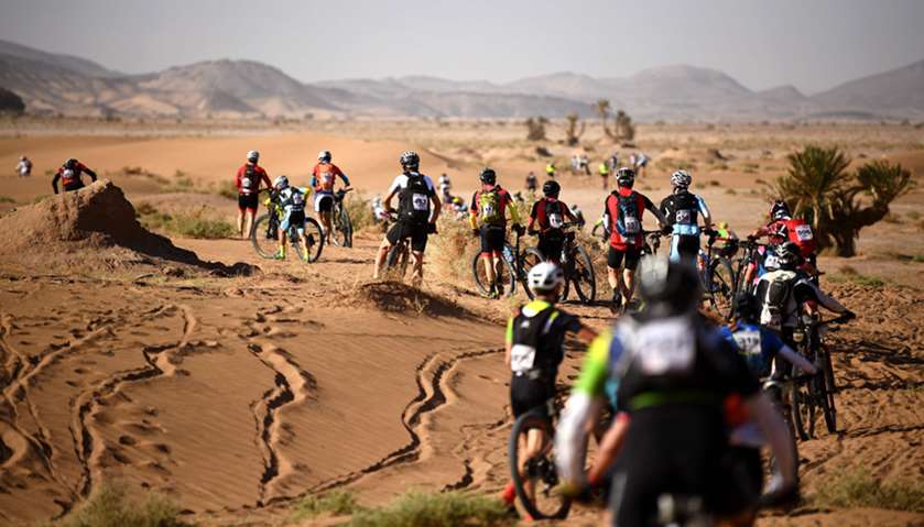 Competitors push their bikes along a sand dune during Stage 4 of the 13th edition of the Titan Deser