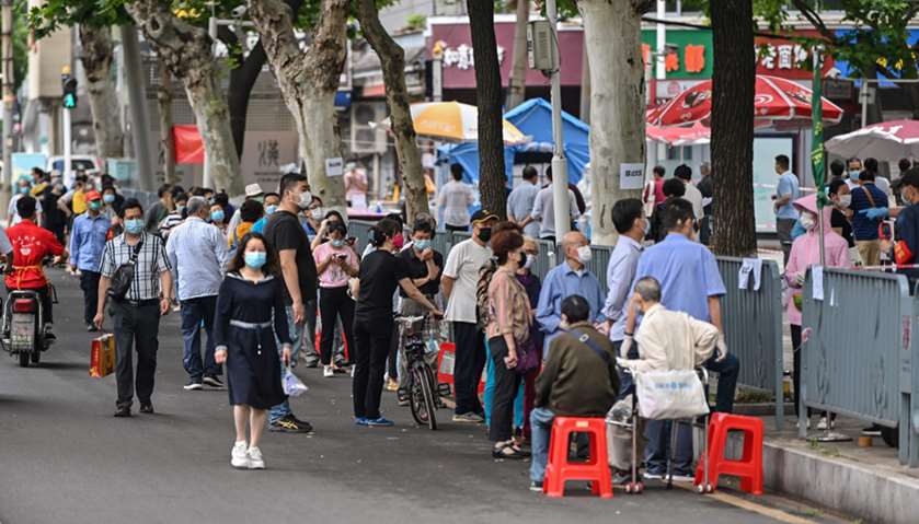 People wearing face masks wait in line to be tested for the  coronavirus on a street in Wuhan