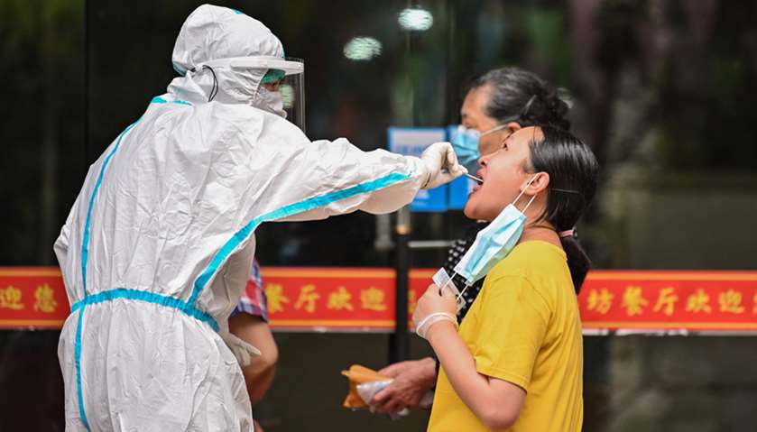 A medical worker takes a swab sample from a man to be tested for coronavirus next to a street in Wuh