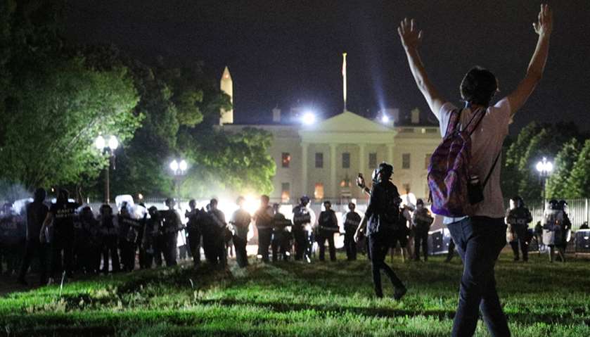 A protester holds his hands up as police officers enter Lafayette Park during a demonstration