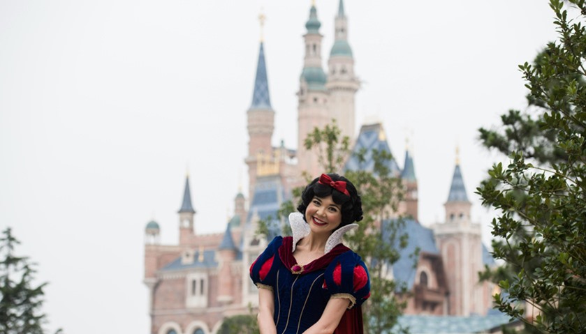 An actress dressed as \'Snow White\' poses in front of the Enchanted Storybook Castle