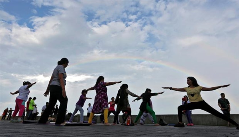 Indians perform yoga as a rainbow is seen in the background on a seafront promenade in Mumbai