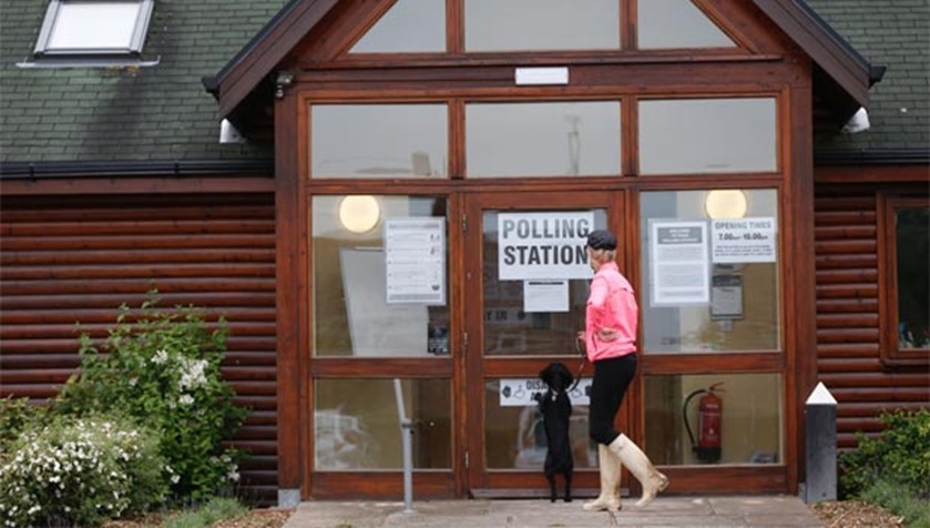A woman waits with her dog outside a polling station in Little Milton on Thursday