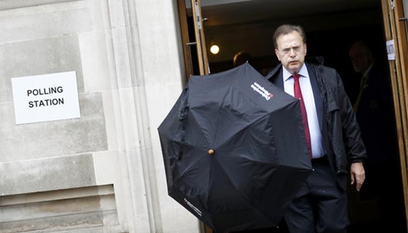 A man carries an umbrella as he leaves a polling station for the referendum on EU in north London