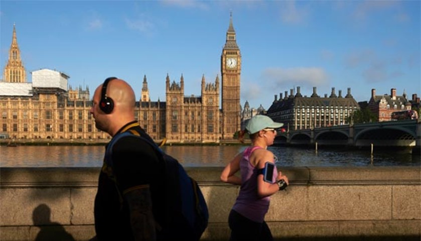 Joggers run along the towpath opposite Big Ben and the Houses of Parliament in London on Friday