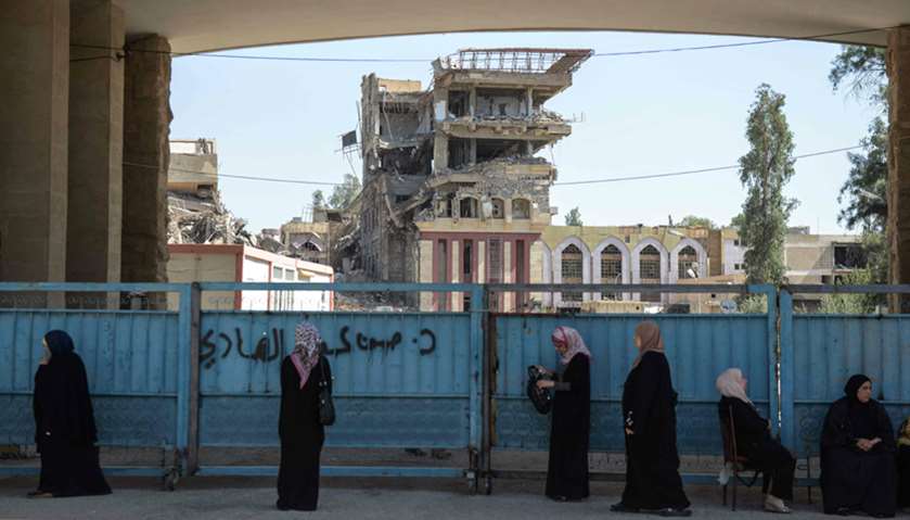 Iraqi women wait outside the University of Mosul as students arrive to take their exams.