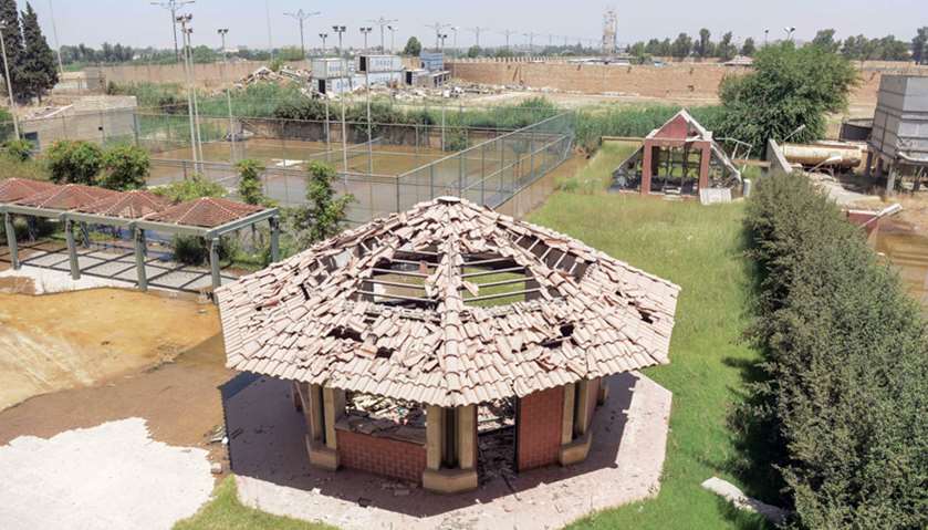 Damaged buildings and a neglected tennis court in the grounds in Iraq