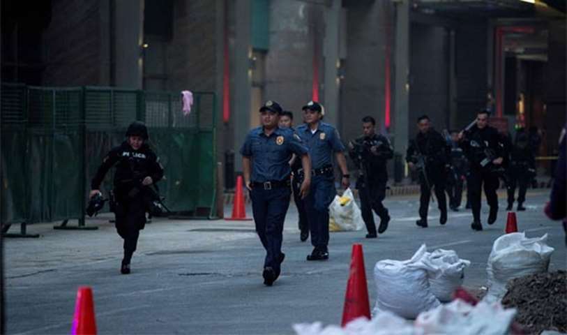 Philippines\' police officers walk in front of the Resorts World Hotel following an assault on Friday