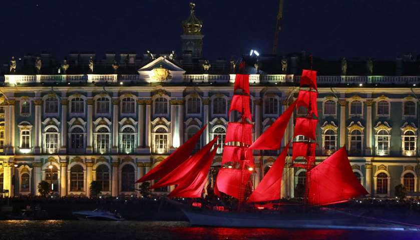 Sweden\'s brig Tre Kronor with scarlet sails floats on the Neva river in front of the Hermitage durin