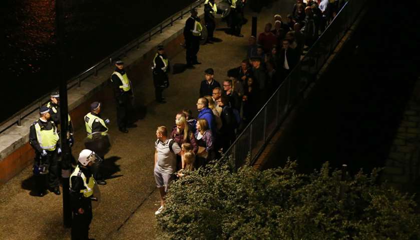 Police officers stand with people evacuated from the area after an incident near London Bridge