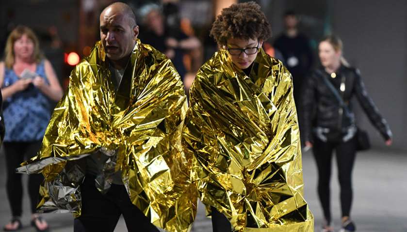 Members of the public, wrapped in emergency blankets leave the scene of a terror attack