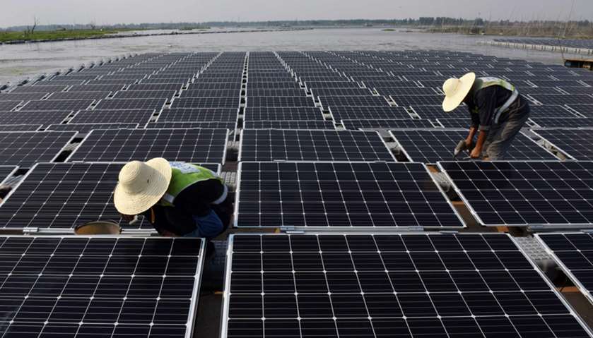 Workers at the world\'s largest floating solar power plant in a lake in Huainan, in China