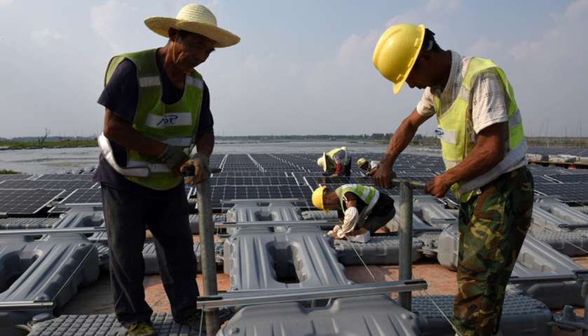 Workers at the world\'s largest floating solar power plant in a lake in Huainan, in China