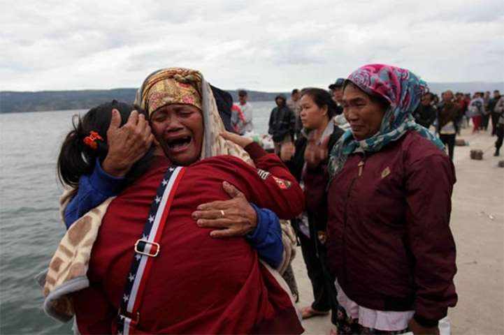 Relatives cry while waiting for news on missing family members who were on a ferry