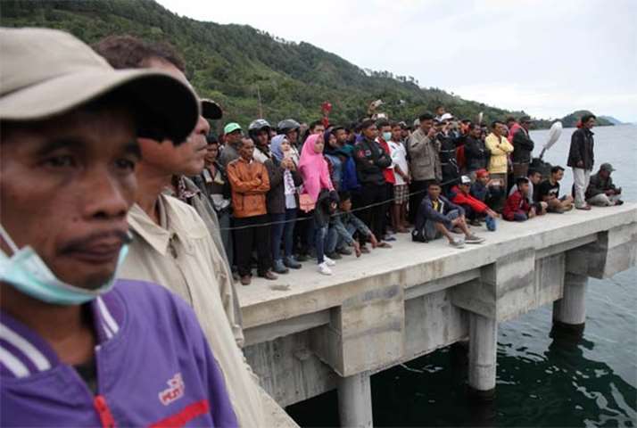 Local residents and relatives of missing passengers wait on the dock at Tigaras Port