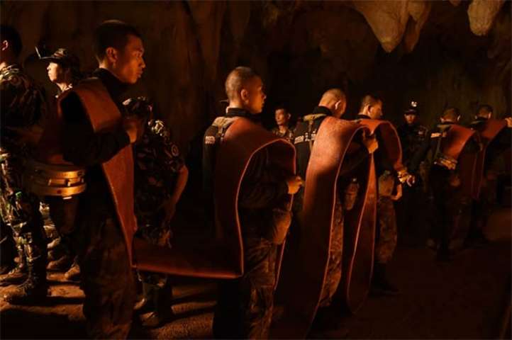 Thai soldiers carry hose deep into the Tham Luang cave to pump out water