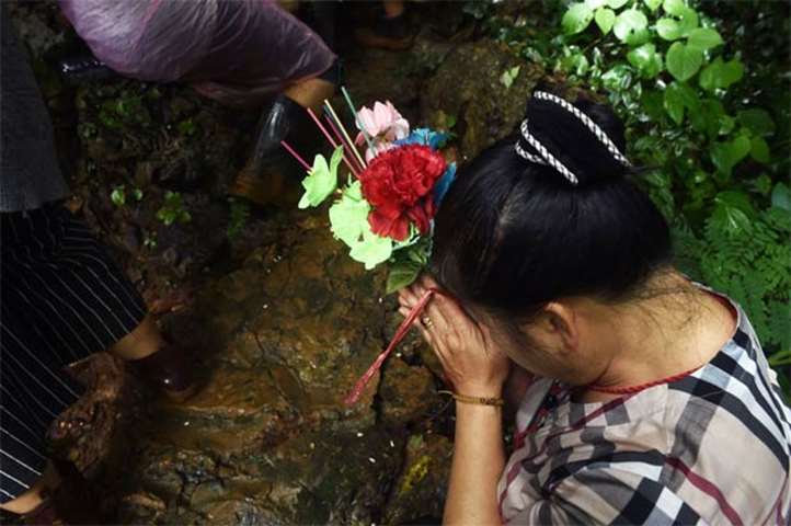 A woman offers a prayer near the Tham Luang cave at the Khun Nam Nang Non Forest Park