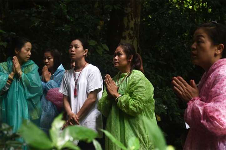 Relatives pray near the Tham Luang cave as rescue operation continues for the missing children