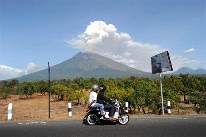 A motorist passes by as Mount Agung volcano erupts on Indonesia\'s resort island of Bali on Friday