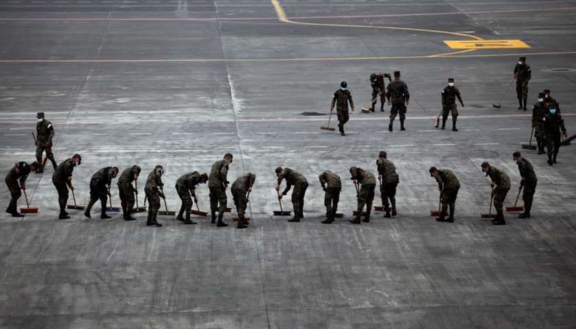 Soldiers sweep the ash covered tarmac at La Aurora International Airport after Fuego erupted
