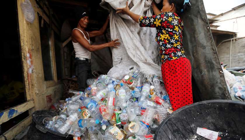A man and a woman sort plastic bottles for recycling at Cilincing district in Jakarta, Indonesia