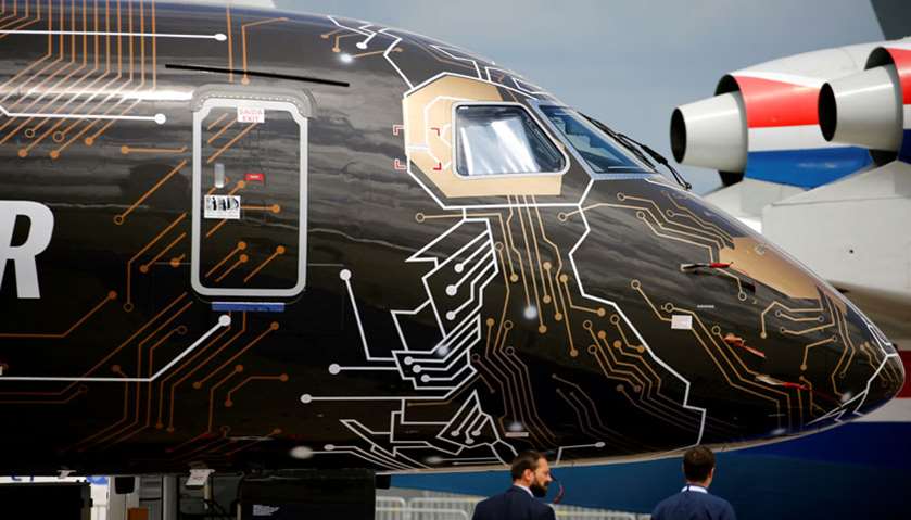 People walk past An Embraer E195-E2 at International Paris Air Show at Le Bourget Airport near