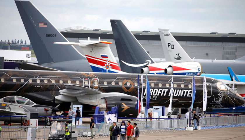 People walk past aircrafts at the eve of the opening of the 53rd International Paris Air Show